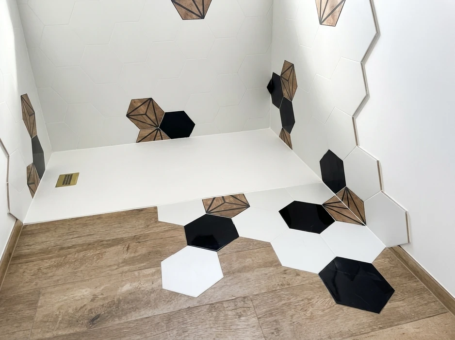 Salle de bain moderne avec carrelage hexagonal blanc en faïence sur murs et sol, agrémenté d'hexagones noirs brillants et de carreaux décoratifs à motif géométrique 3D imitation bois