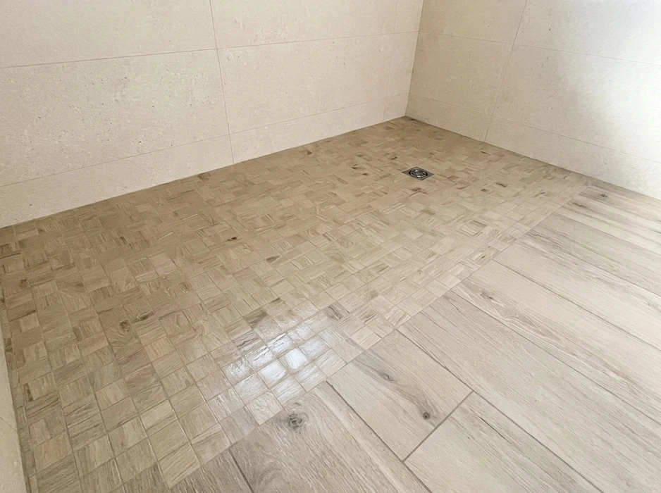 Douche à l'italienne avec sol en mosaïque de carrelage imitation bois, format petit module carré, avec drain central carré chromé